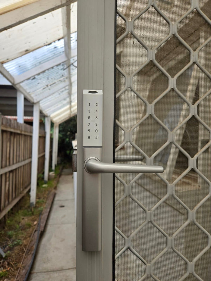 Slim silver smart lock with keypad and lever handle, installed on a security screen door, offering secure keyless entry while maintaining airflow and visibility.